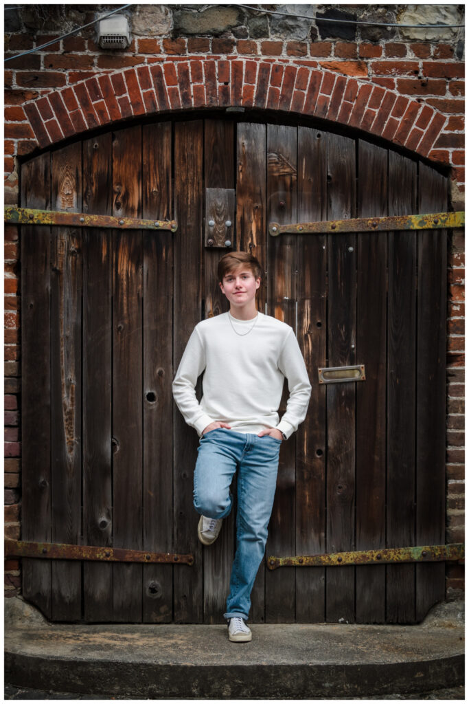 Boy leaning on a wood door for senior portraits
